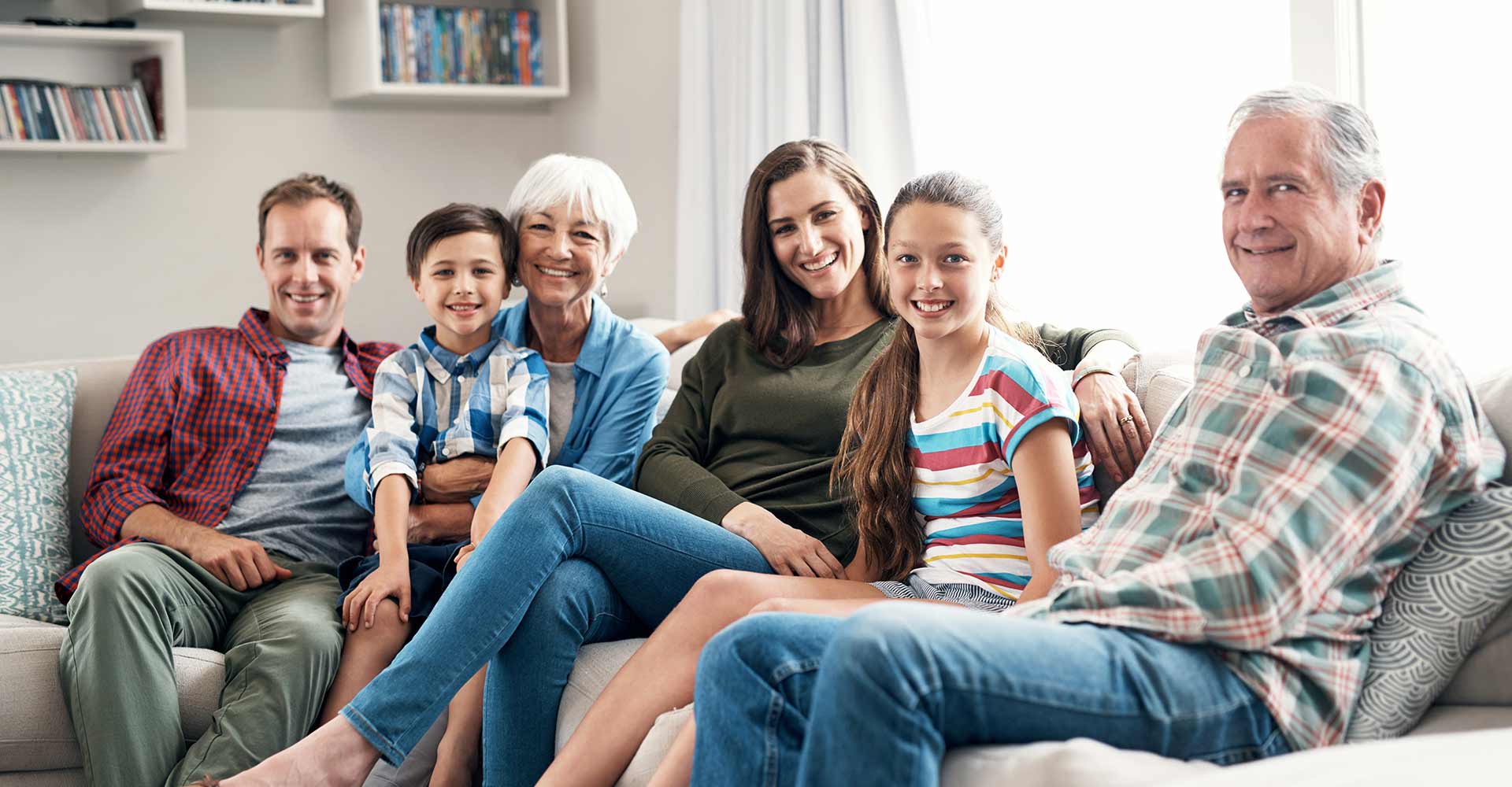 3 generations sitting on couch smiling