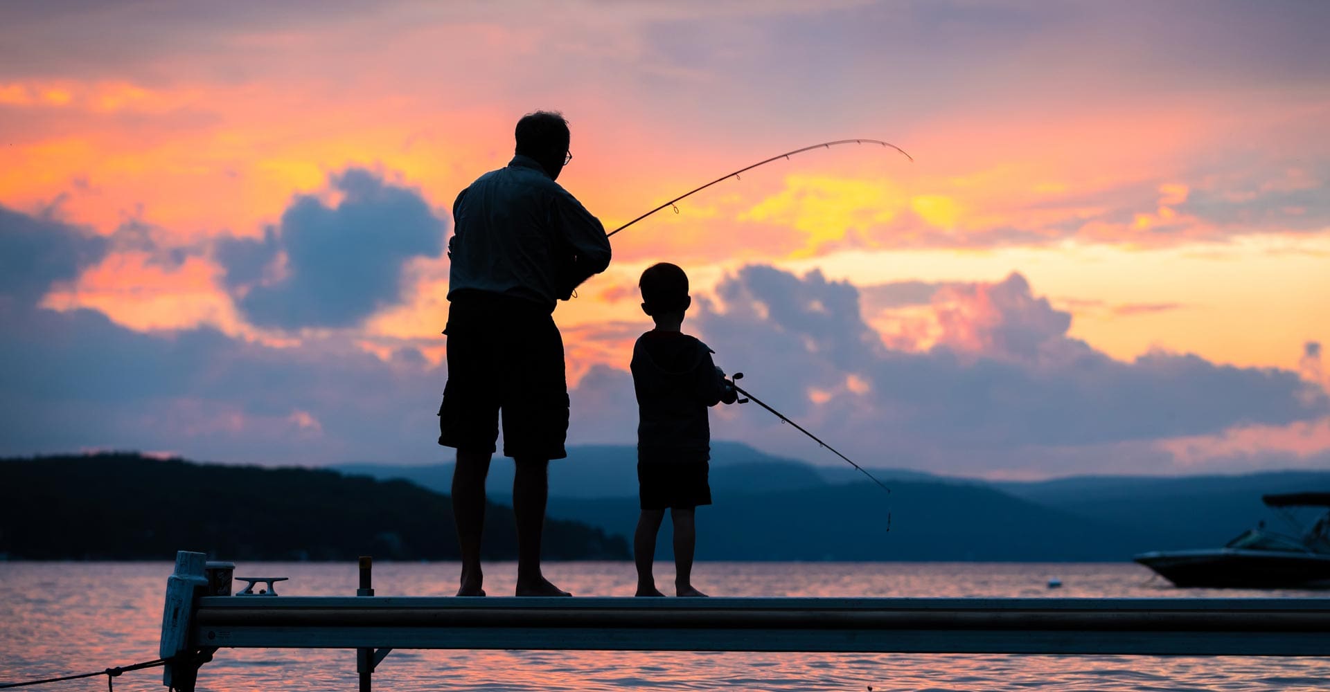 Silhouette of grandad and grandchild fishing at sunset
